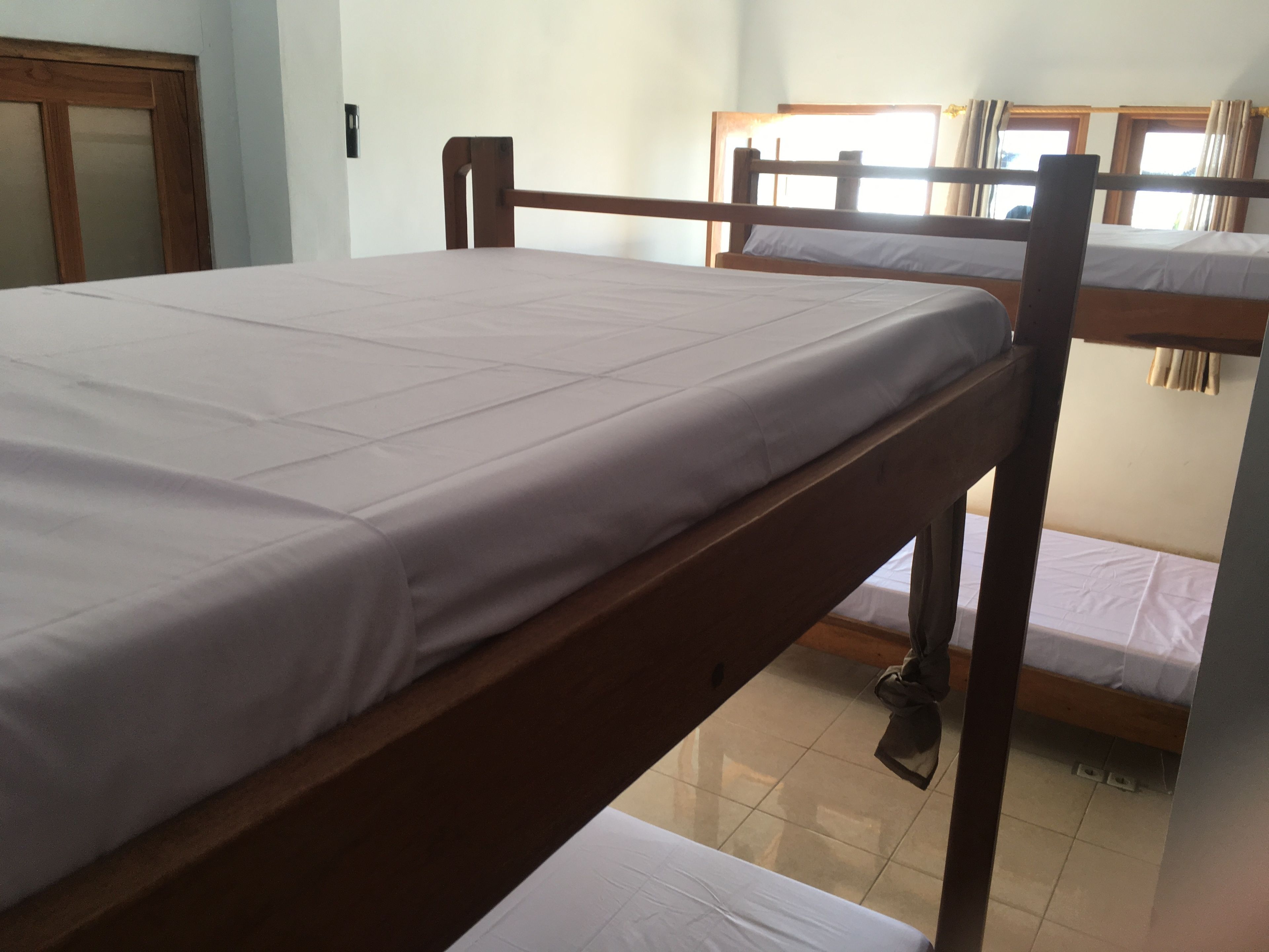 Un dormitorio con literas, una puerta de madera y una ventana con cortinas.