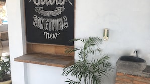 A room with a blackboard displaying motivational text, a potted plant, a wooden stool, and a brick wall. - Bajo Sunset Hostel (Labuan Bajo)