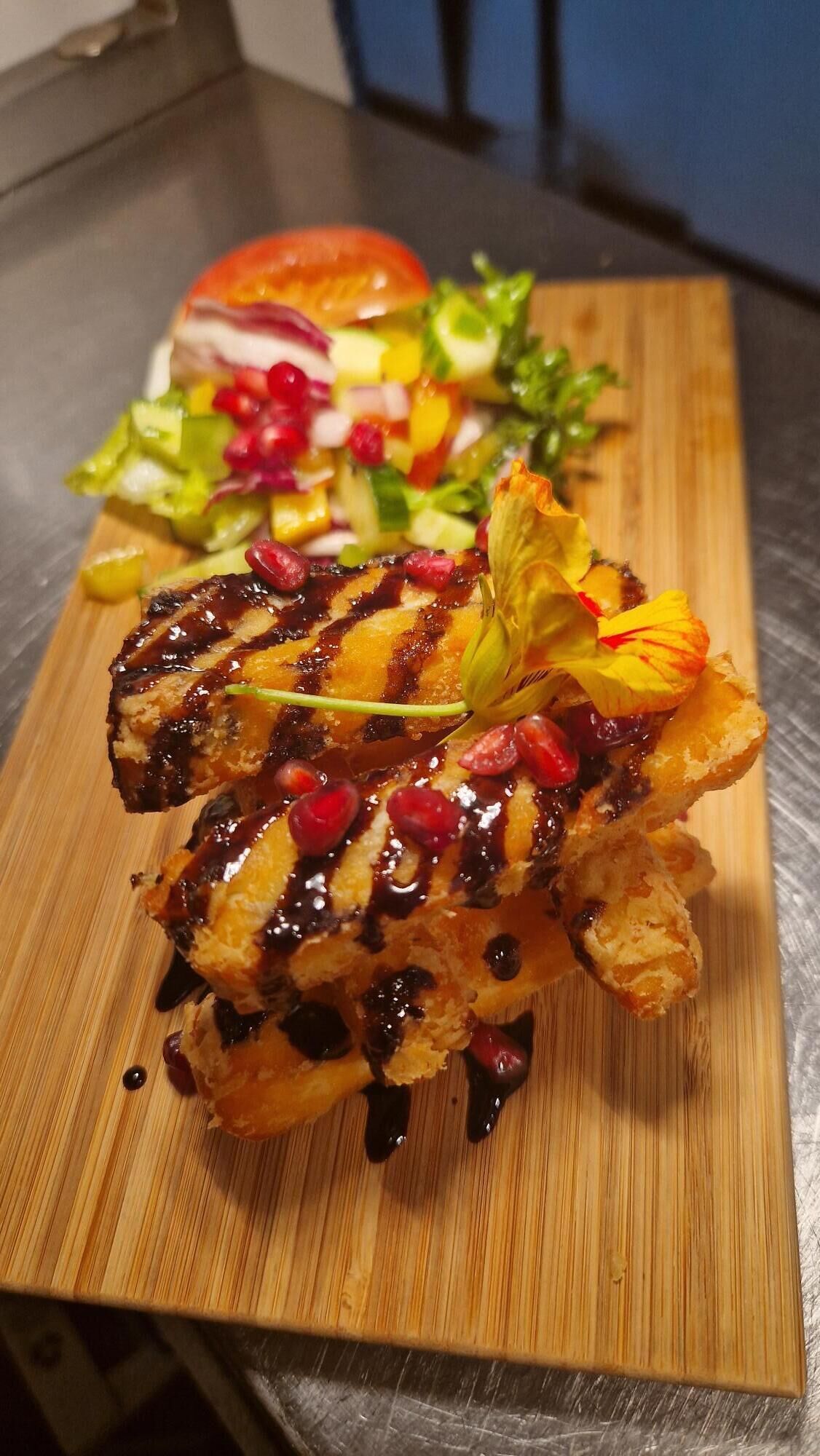 Un plato con pollo a la parrilla, ensalada y una hamburguesa sobre una tabla de madera.