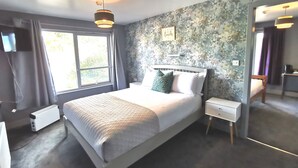 A bedroom with a bed, bedside tables, a radiator, a window, and a mirror. - Lunan House (Arbroath)