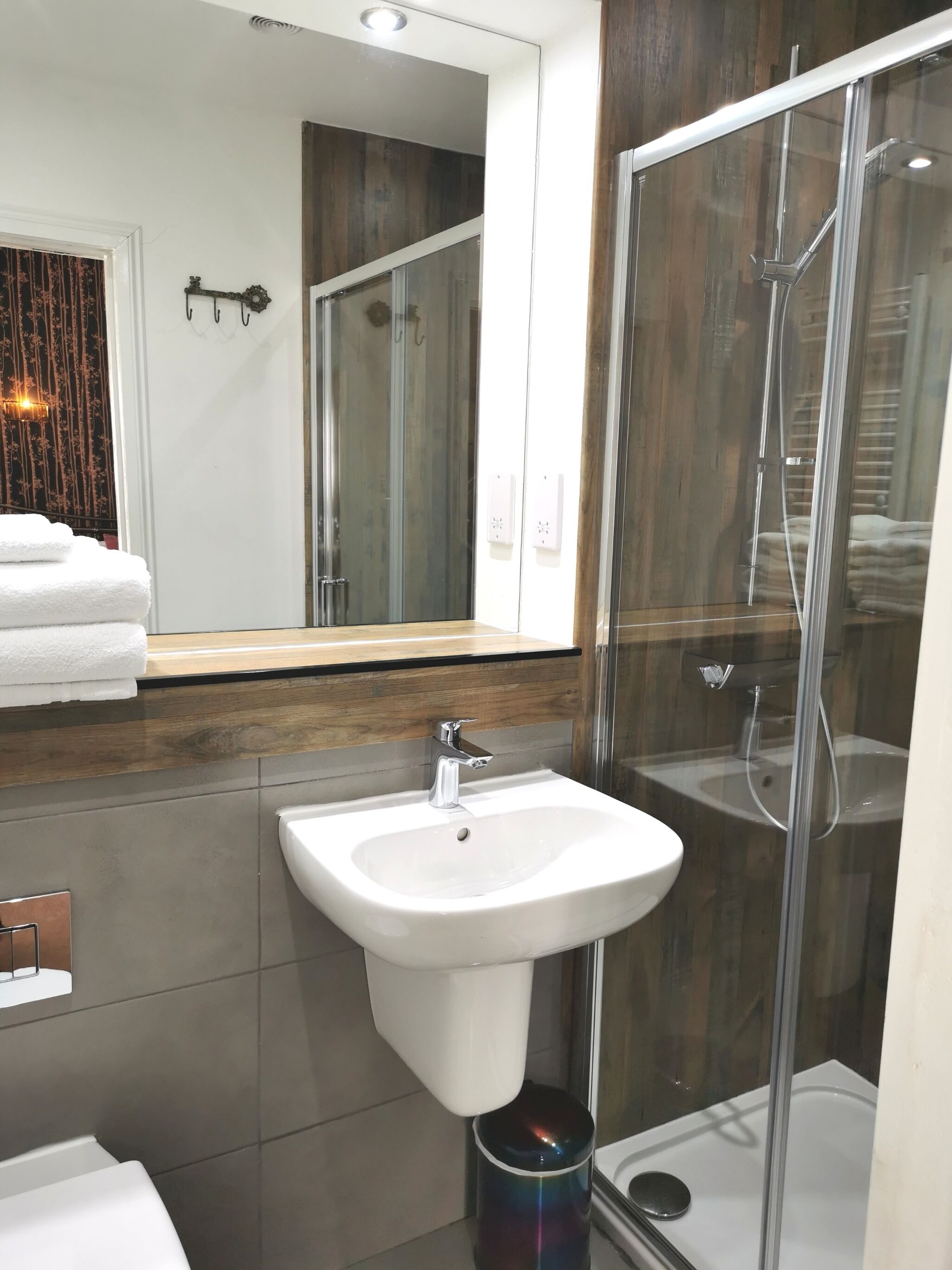 Un baño moderno con cabina de ducha de vidrio, lavabo blanco y tocador de madera.
