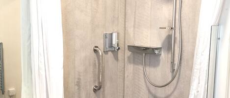 Un baño con ducha, lavamanos y espejo.