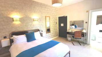 A hotel room with a bed, bedside table, desk, chair, and a mirror.