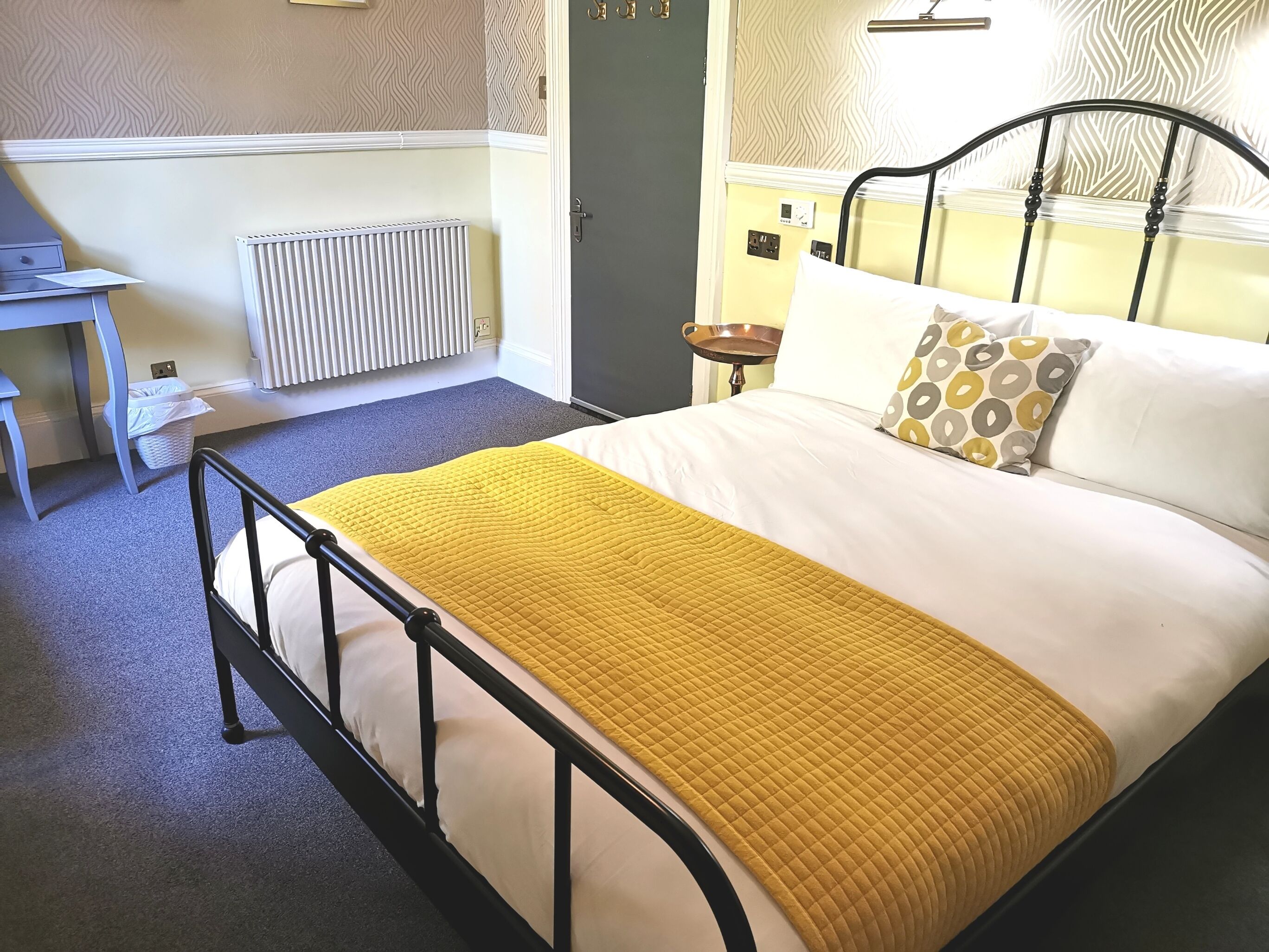 A neatly arranged bedroom with a bed, bedside table, and a radiator.