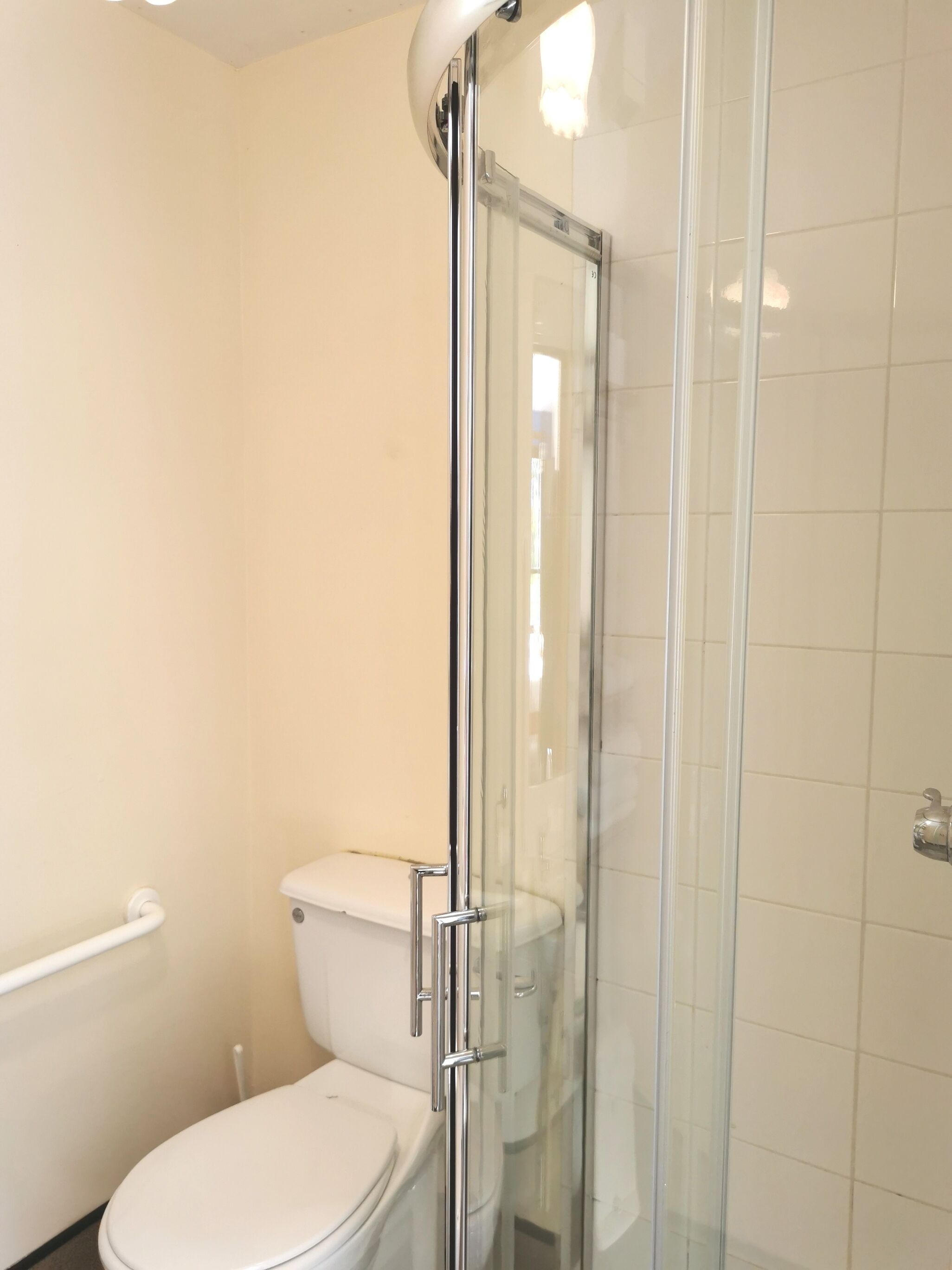 A bathroom with a glass-enclosed shower, a white toilet, and a white sink.