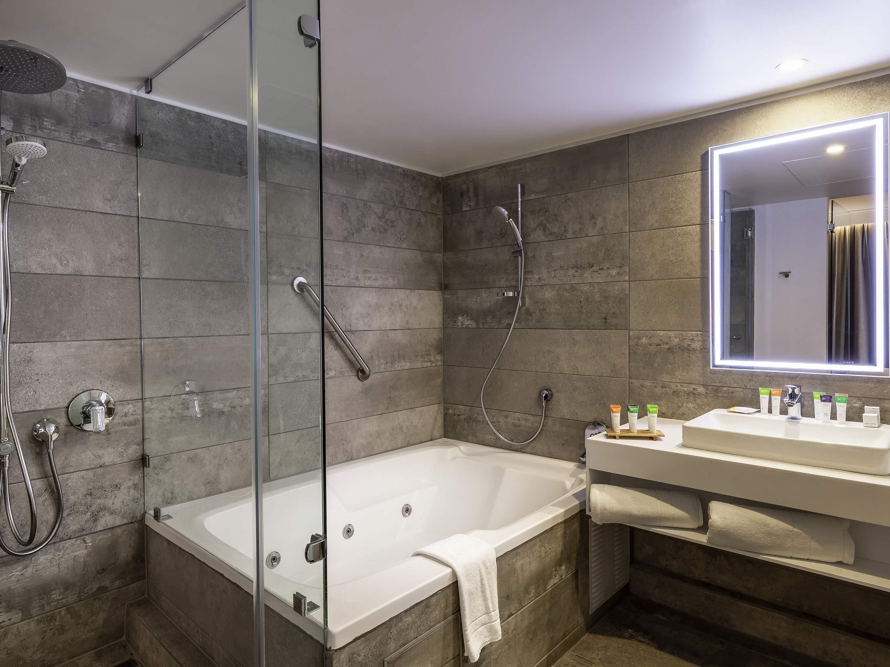A modern bathroom with a glass-enclosed shower, a standalone bathtub, and a vanity with a mirror.