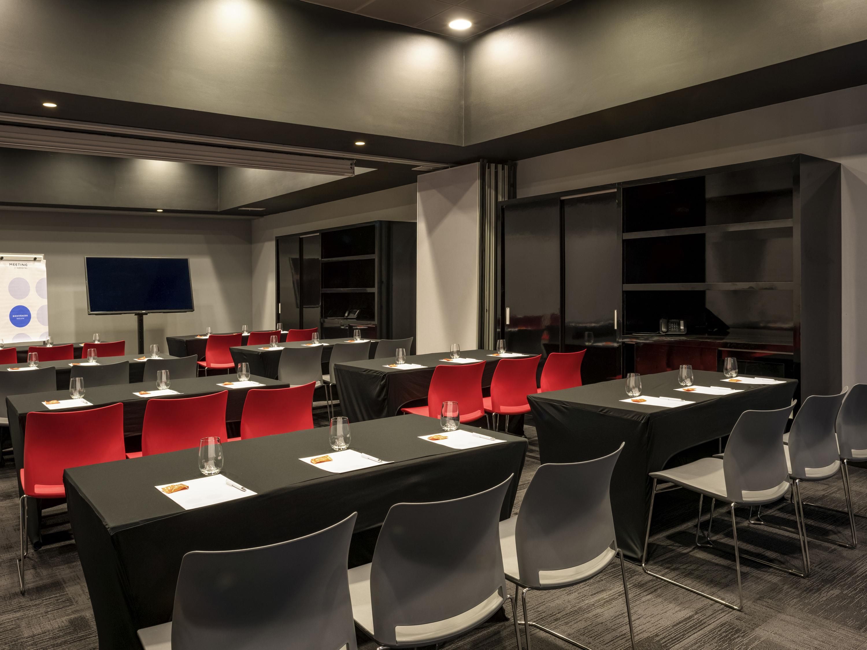 A conference room with tables, chairs, a projector screen, and a presentation screen.