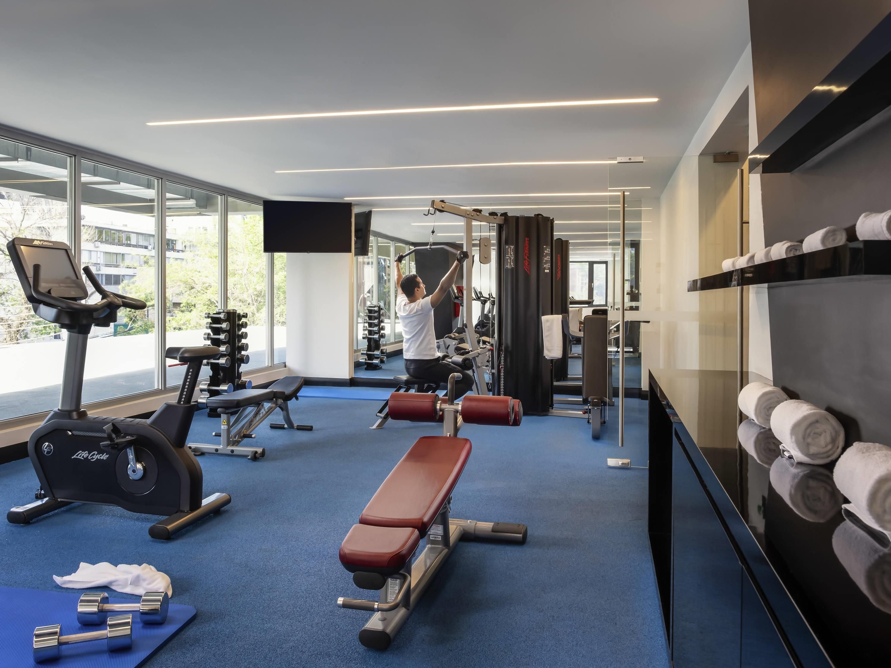 A gym with exercise equipment, a bench, and a wall-mounted towel rack.