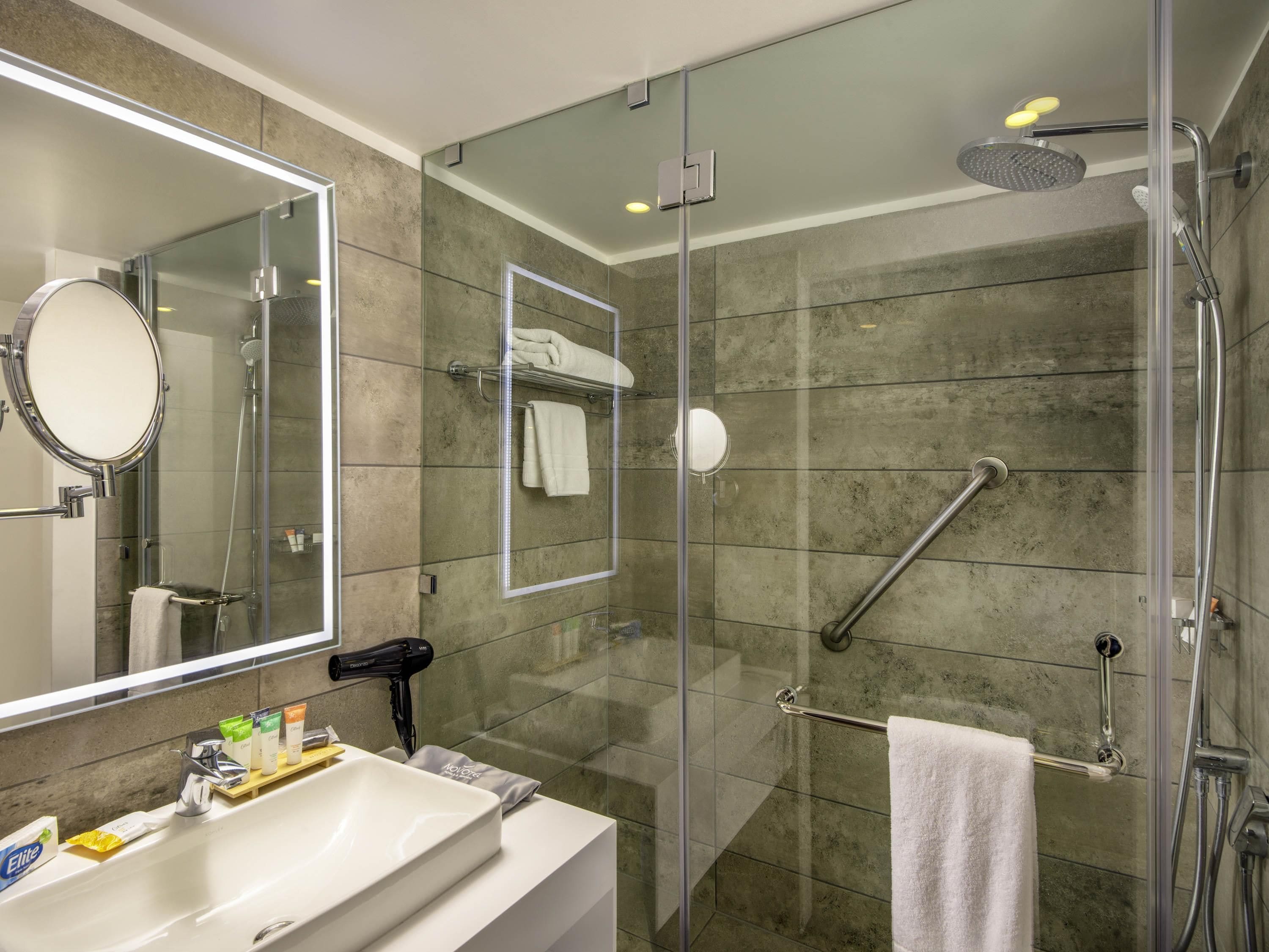 A modern bathroom with a glass-enclosed shower, a vanity with a sink, and a mirror.