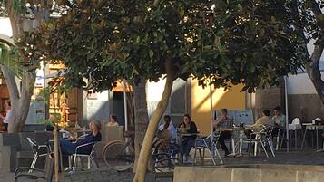 An outdoor café with tables and chairs, surrounded by trees and buildings.