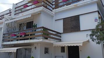 A multi-story residential building with balconies, potted plants, and a gated entrance.