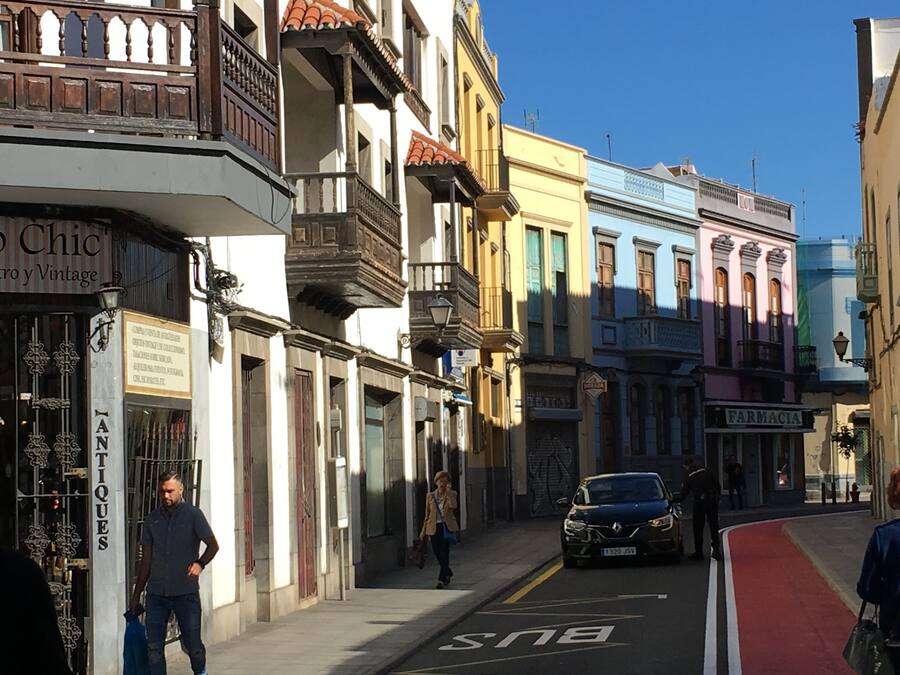 A street with buildings, a bus lane, and pedestrians.