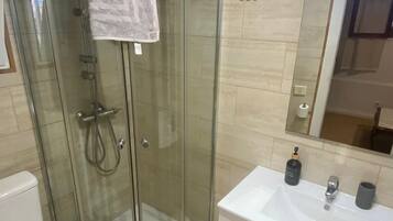 Een moderne badkamer met een douchecabine van glas, een wit toilet en een wastafel met een spiegel.