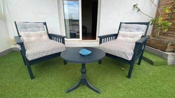 A patio with two chairs and a table, surrounded by artificial grass.