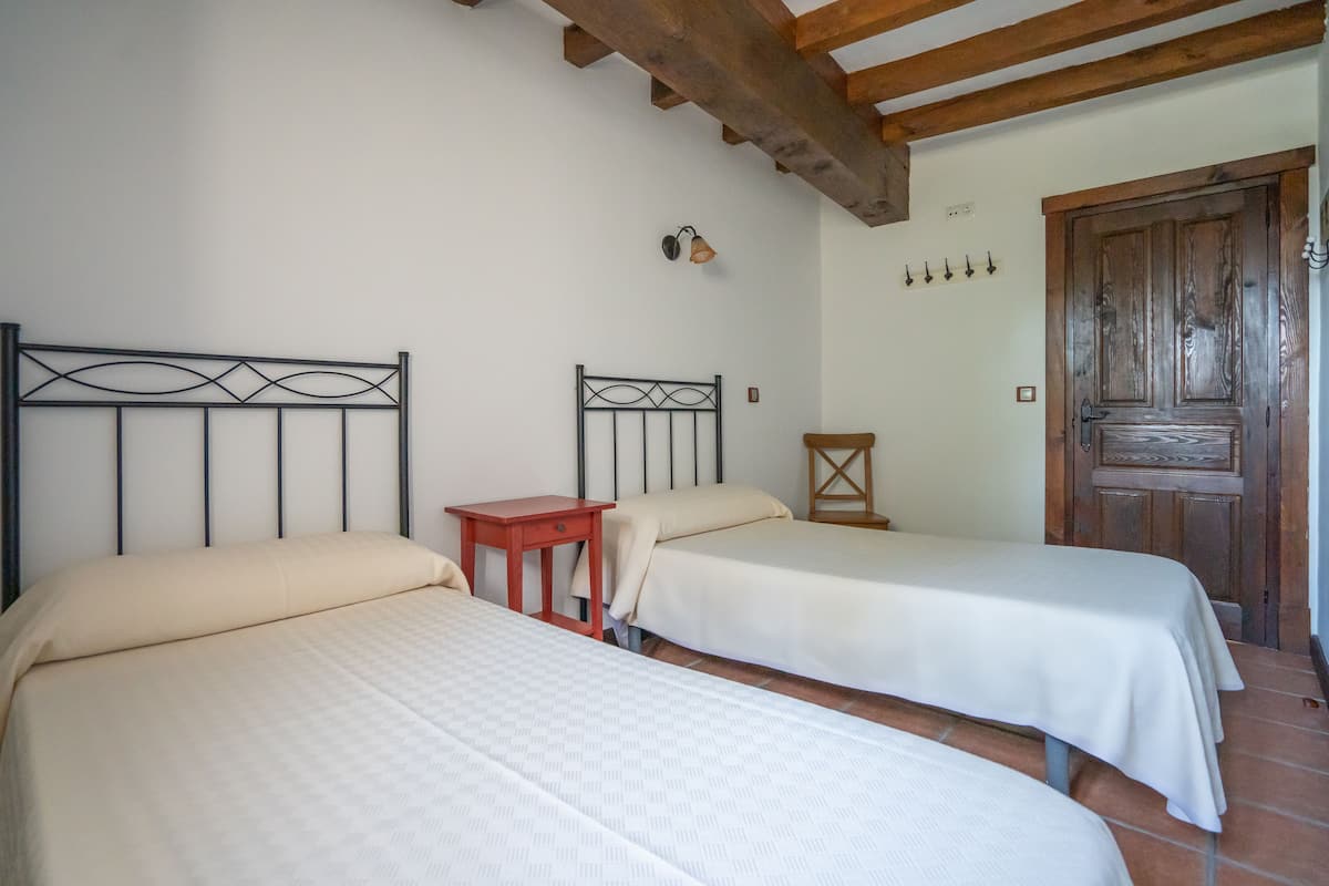 Ein Zimmer mit zwei Betten, einer Holztür und einer Wandleuchte.