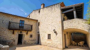 Un bâtiment en pierre doté d’un balcon et d’une arche donnant sur un patio abrité.