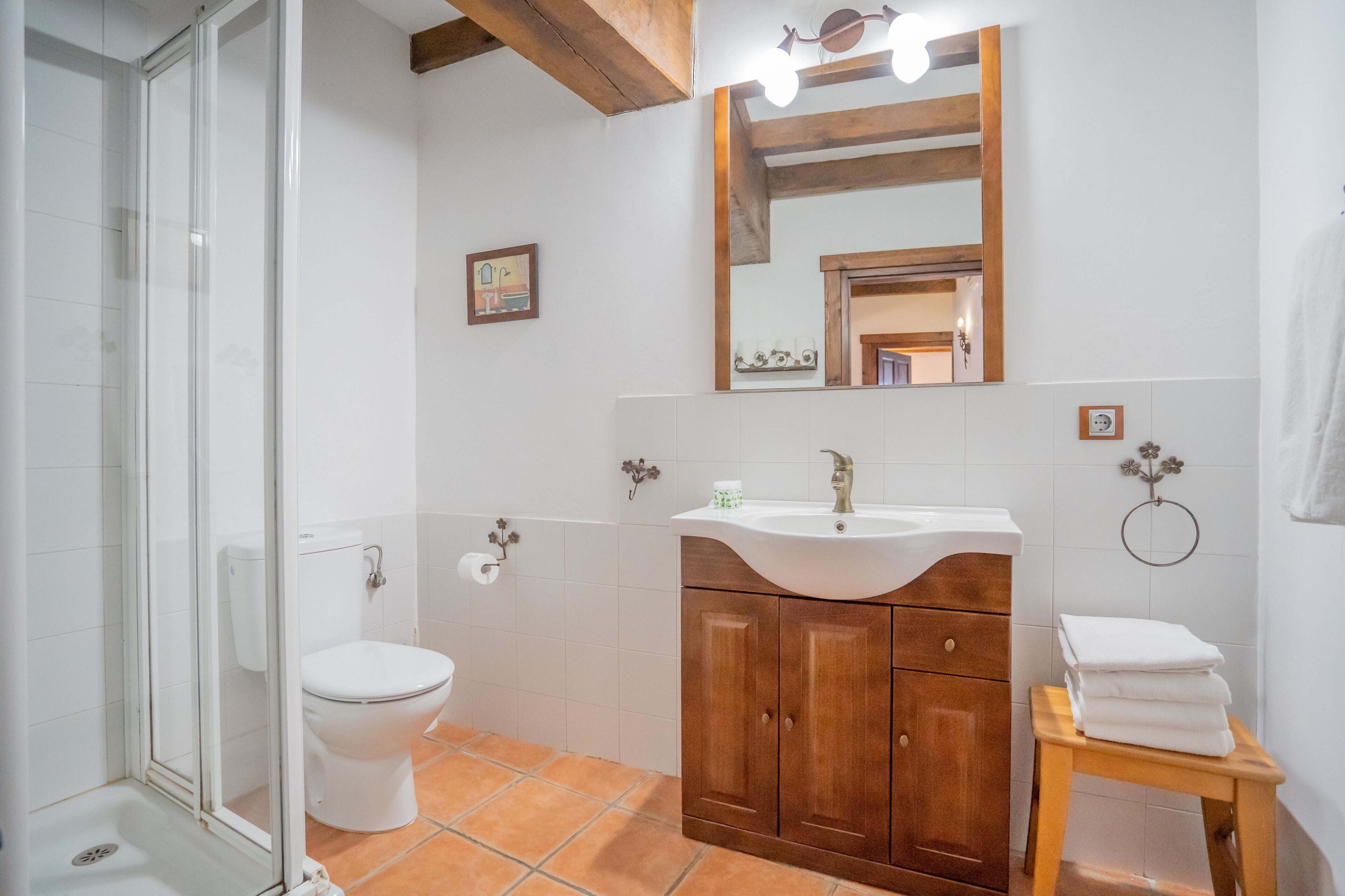 Een badkamer met toilet, wastafel, houten kast en een klein houten krukje.
