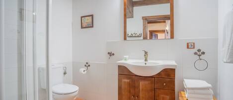 Een badkamer met toilet, wastafel, houten kast en een klein houten krukje.