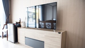 Une chambre moderne équipée d’un téléviseur à écran plat fixé à un meuble en bois, d’un petit réfrigérateur et d’une chaise.