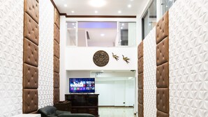 Un salon moderne avec un plafond haut, un téléviseur à écran plat et un élément décoratif mural.