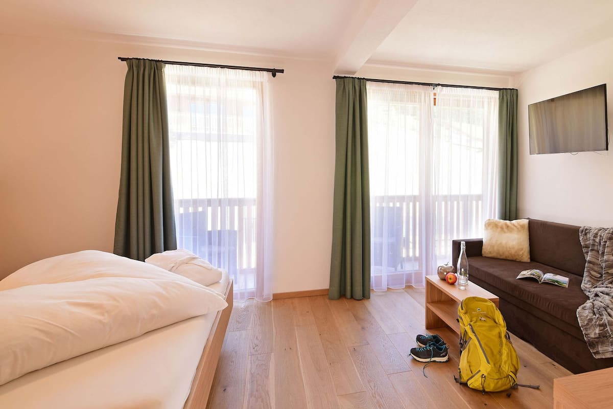Une chambre d’hôtel avec un lit, un canapé, une table en bois et un sac à bagages.