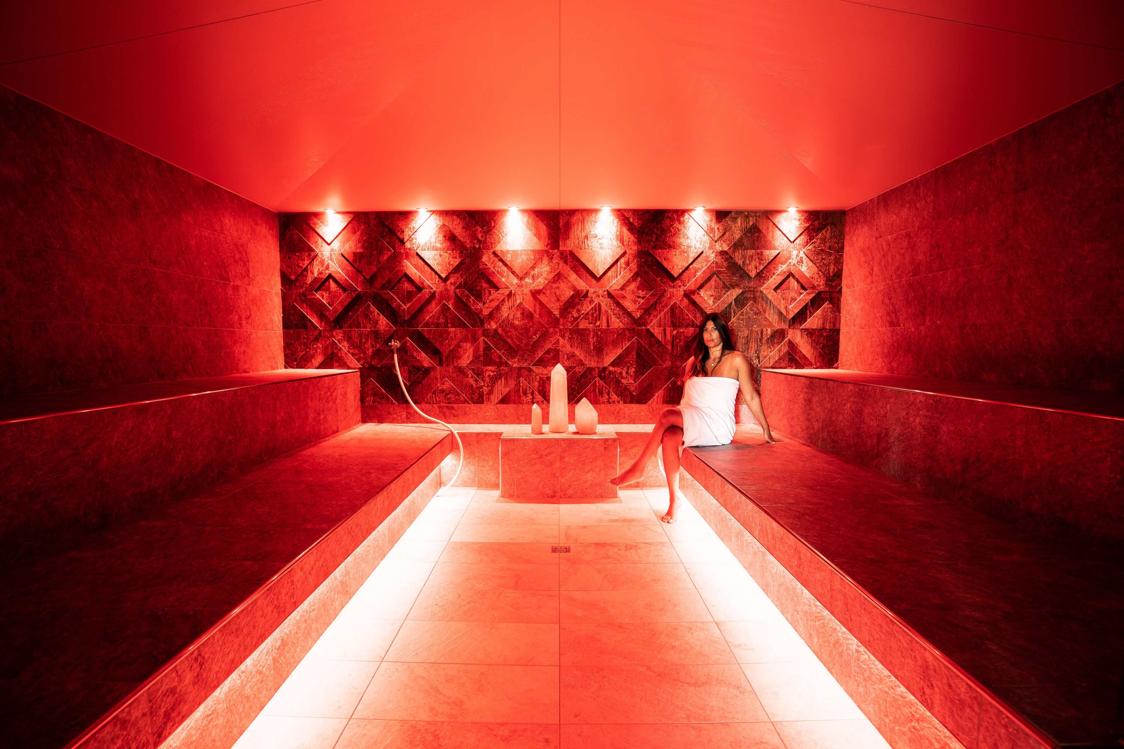 Un'area spa con pareti rosse, una zona salotto centrale e un motivo decorativo sulle pareti.