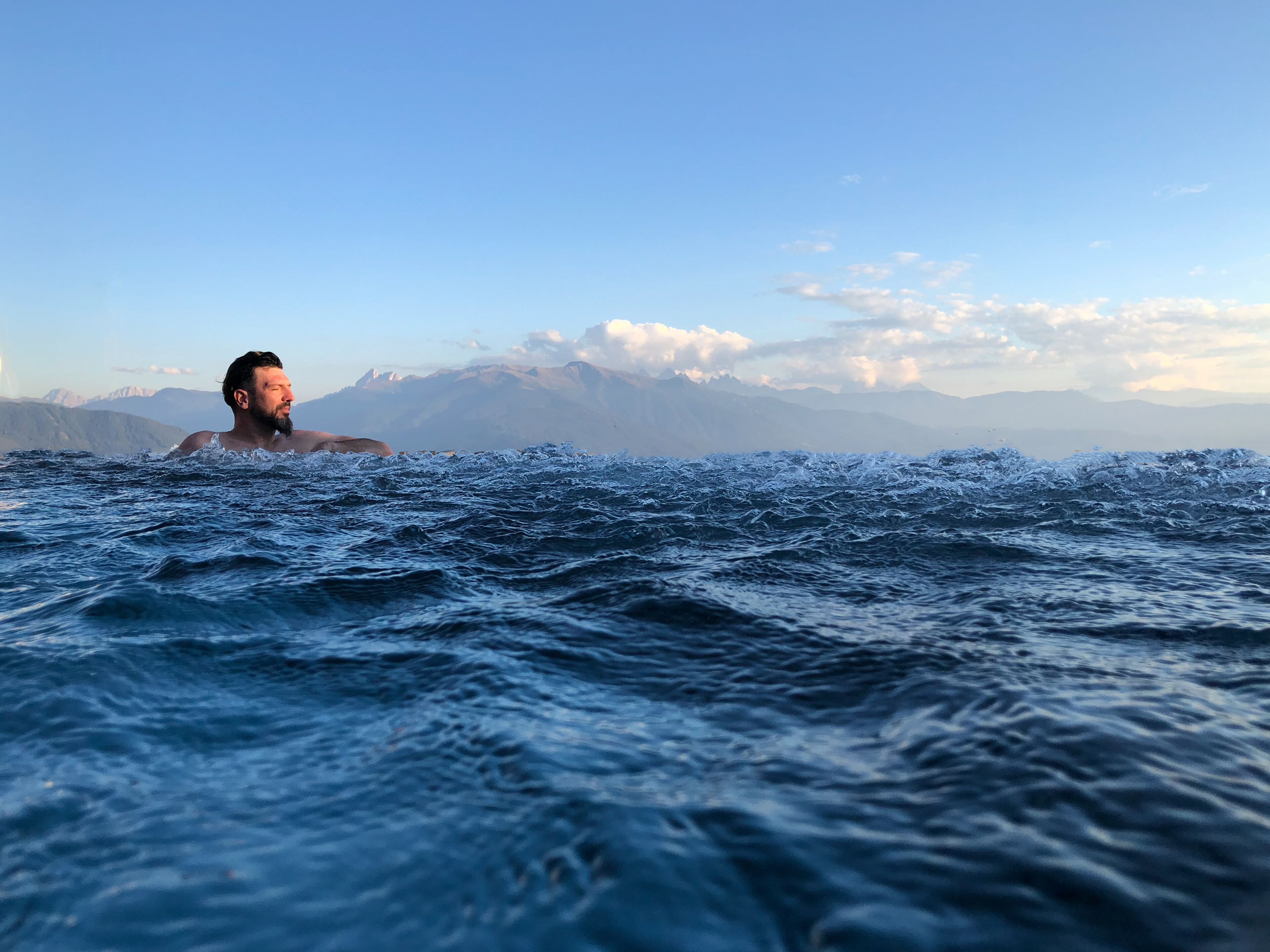Eine Person schwimmt im Wasser, im Hintergrund Berge.