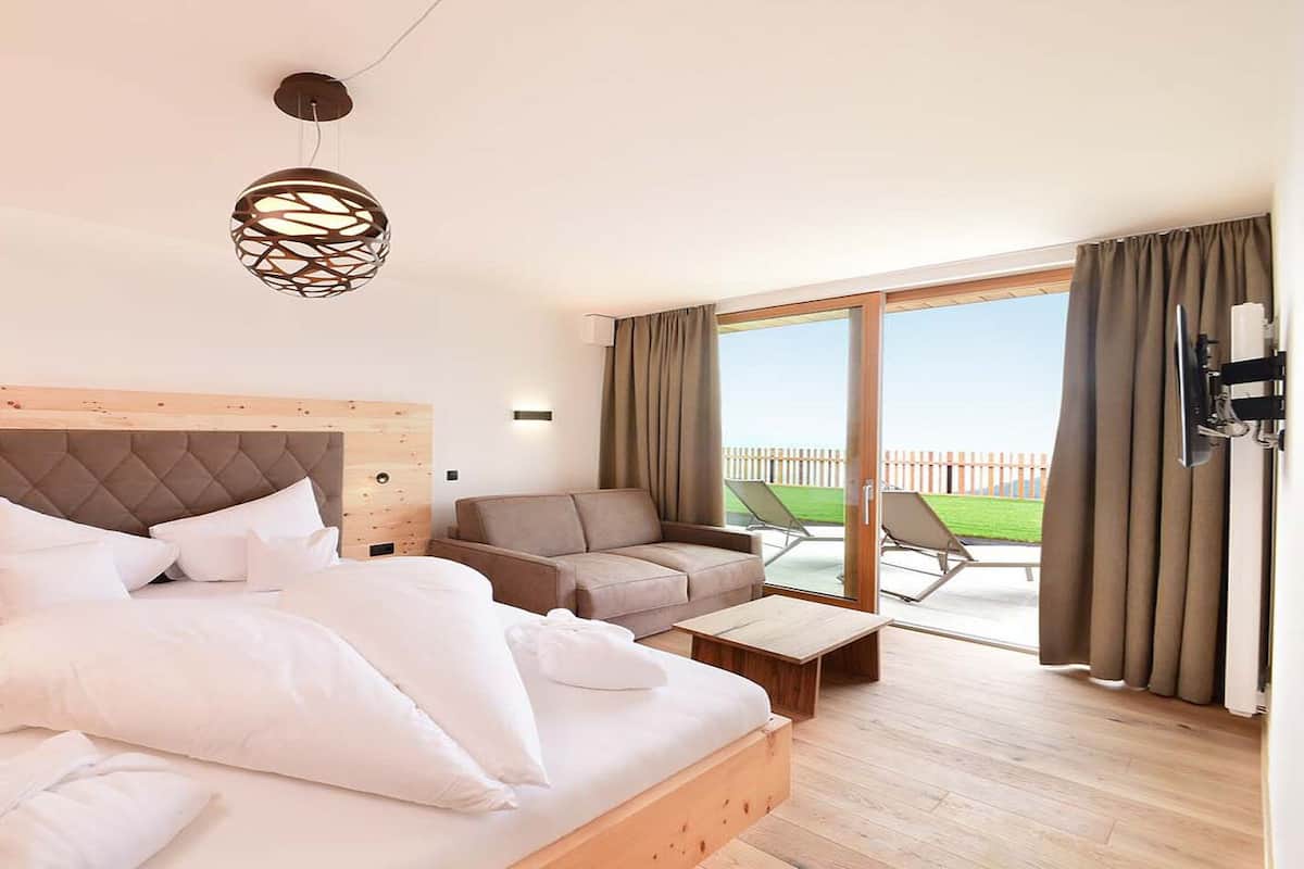 Une chambre moderne avec un grand lit, un canapé, une petite table et un balcon avec vue.