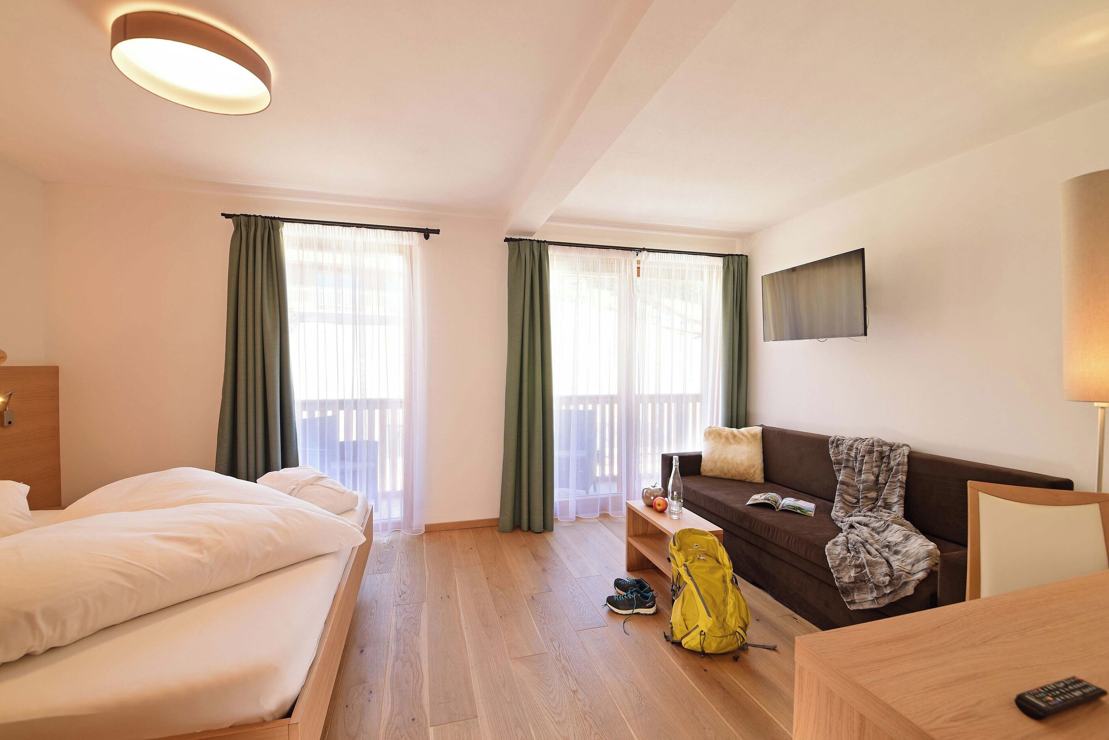 Una camera d'albergo con un letto, un divano, un tavolo e una televisione.