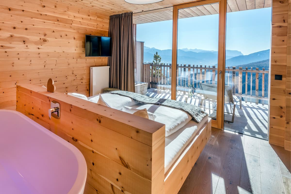 Une cabane en bois dotée d’une grande baignoire, d’un lit avec vue et d’un balcon orné d’une balustrade en bois.