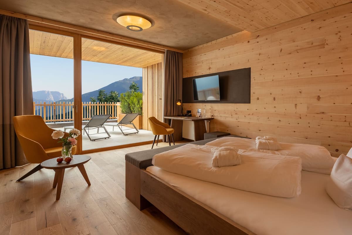 Une chambre d’hôtel équipée d’un lit, d’un bureau, d’une télévision et d’un balcon avec des chaises et une table.