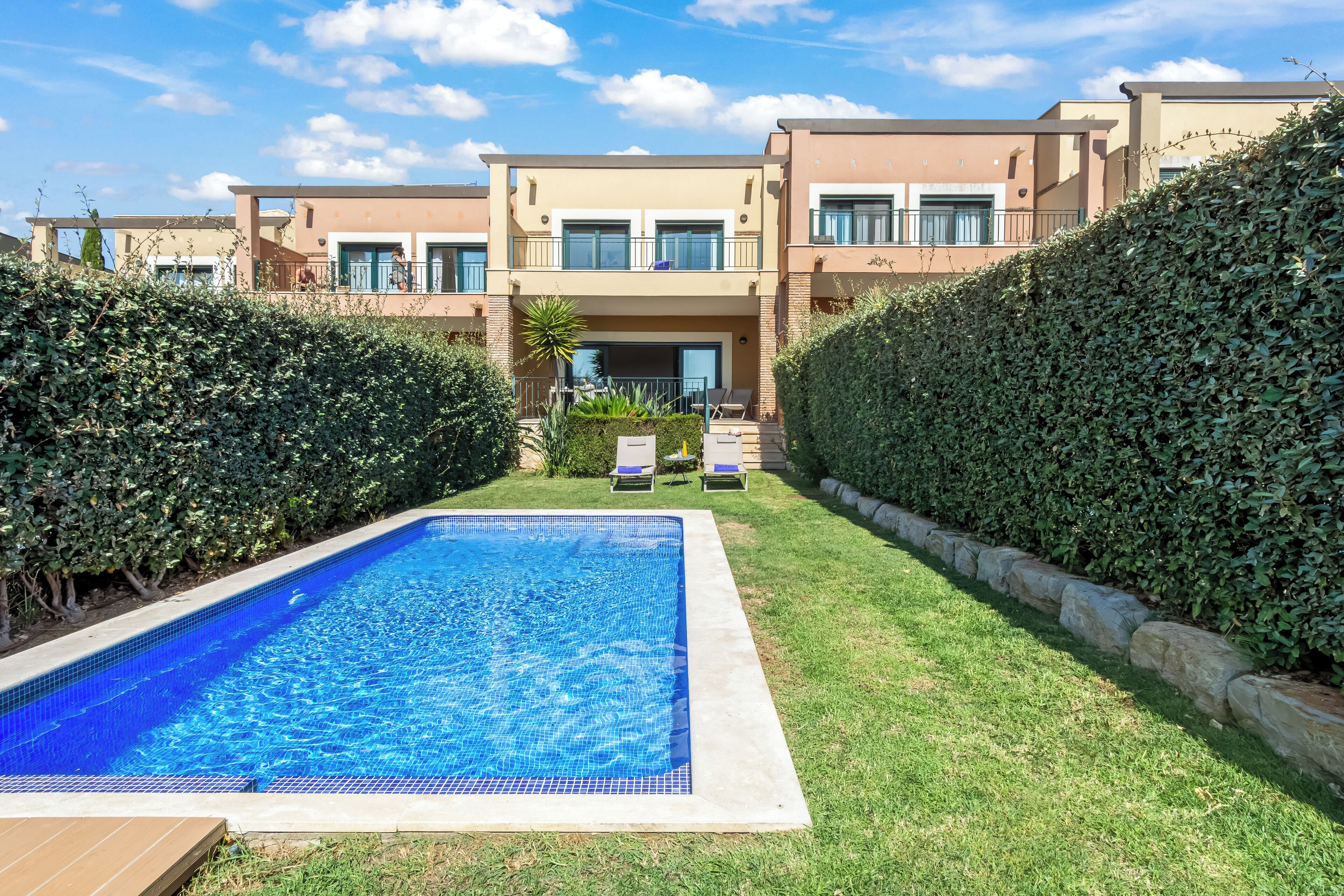 A swimming pool surrounded by a well-maintained lawn, with a building in the background.