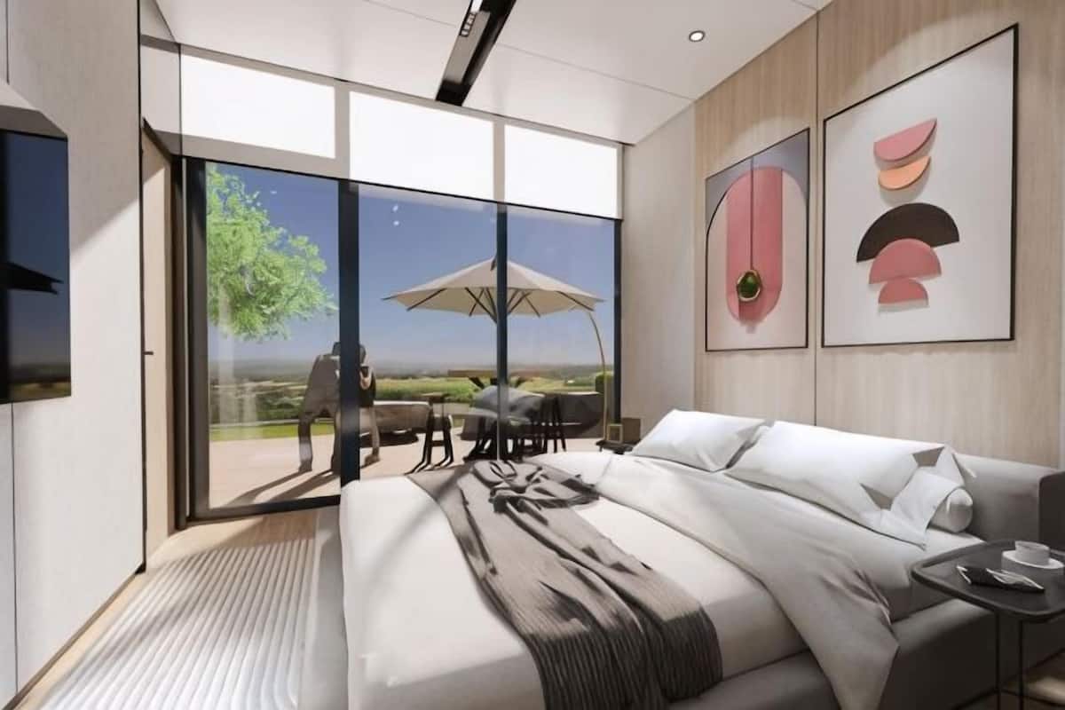 Ein modernes Schlafzimmer mit einem großen Bett, einer Schiebetür zum Balkon und Kunstwerken an den Wänden.