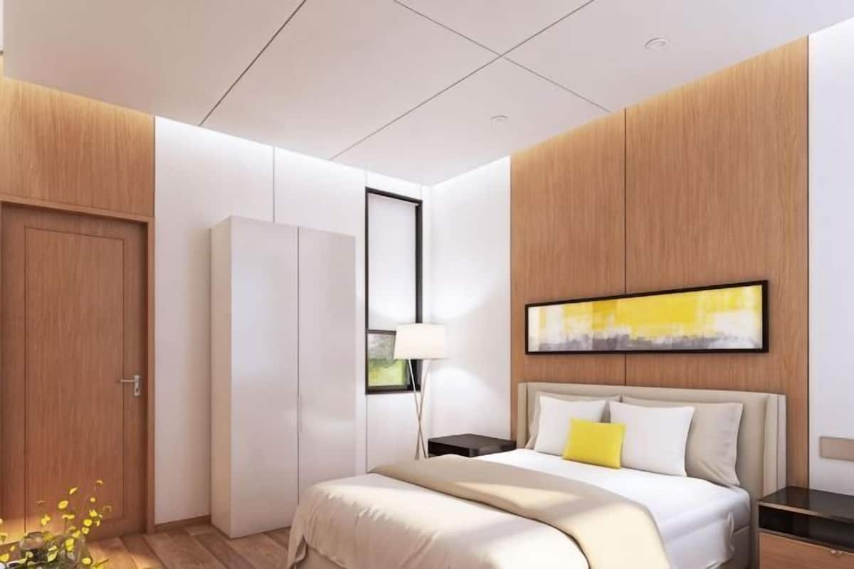 Ein modernes Hotelzimmer mit Bett, Kleiderschrank, Nachttisch und einem Bild an der Wand.