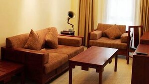 A living room with a sofa, armchair, and coffee table. There is a lamp on a side table. - Jiangnanchun Hot Spring Resort Hotel (Zhengzhou)