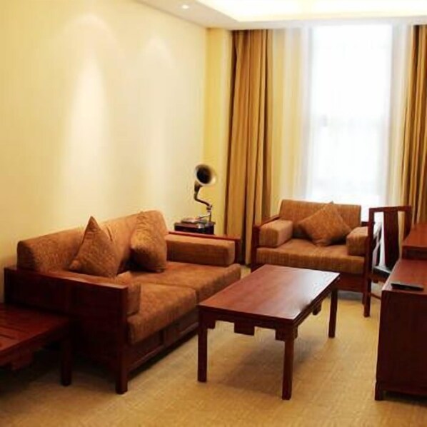 Sala de estar com sofá, poltrona e mesa de centro. Há uma luminária em uma mesinha lateral.