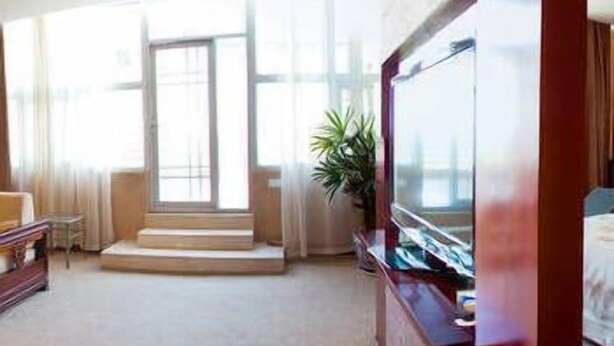 A hotel room with a large TV, a sofa, a coffee table, and a staircase leading to an outdoor area. - Jiangnanchun Hot Spring Resort Hotel (Zhengzhou)