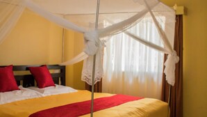 A double bed with a canopy, red pillows, and a red throw blanket. - Kifaru House - Karen (Nairobi)