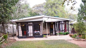 A two-story house with a covered porch, a stone foundation, and a small garden area. - Kifaru House - Karen (Nairobi)