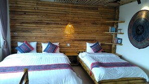 Une chambre avec deux lits, des murs en bois, un luminaire suspendu et une tapisserie murale tissée.
