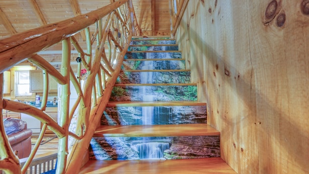 A wooden staircase with a wooden railing and a view of a kitchen area. - Bear Pause - 2 Bedrooms, 2 Baths, Sleeps 6 Cabin by RedAwning (Sevierville)