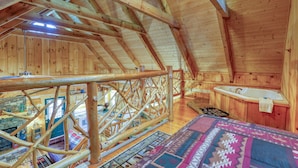 A wooden cabin with a loft bedroom, a stone fireplace, and a hot tub. - Bear Pause - 2 Bedrooms, 2 Baths, Sleeps 6 Cabin by RedAwning (Sevierville)