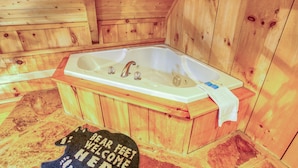 A wooden cabin with a large bathtub, a towel, and a welcome mat. - Bear Pause - 2 Bedrooms, 2 Baths, Sleeps 6 Cabin by RedAwning (Sevierville)