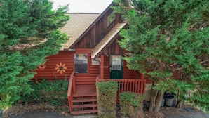 Eine rustikale Holzhütte mit einer grünen Tür und einer kleinen Veranda.