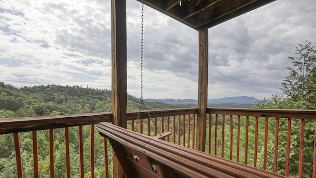 Eine Holzterrasse mit einer Bank, die auf einen bewaldeten Ausblick blickt.