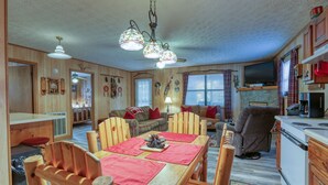 A cozy cabin interior with a wooden dining table, chairs, a sofa, and a kitchen area. - Wandering Creek - 2 Bedrooms, 1 Baths, Sleeps 6 Cabin by RedAwning (Cosby)