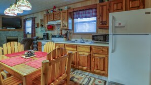 A wooden kitchen with a dining table, chairs, a refrigerator, a microwave, and a stove. - Wandering Creek - 2 Bedrooms, 1 Baths, Sleeps 6 Cabin by RedAwning (Cosby)
