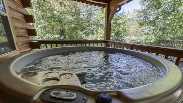 Ein Whirlpool mit einer Holzterrasse und Blick auf Bäume.