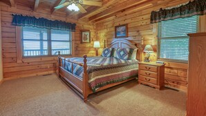 A wooden cabin bedroom with a bed, dresser, and ceiling fan. - Mountain View - 2 Bedrooms, 2 Baths, Sleeps 6 Cabin by RedAwning (Cosby)