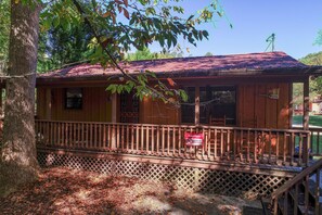 Une cabane en bois avec un toit rouge, une terrasse en bois et un panneau d’avertissement.